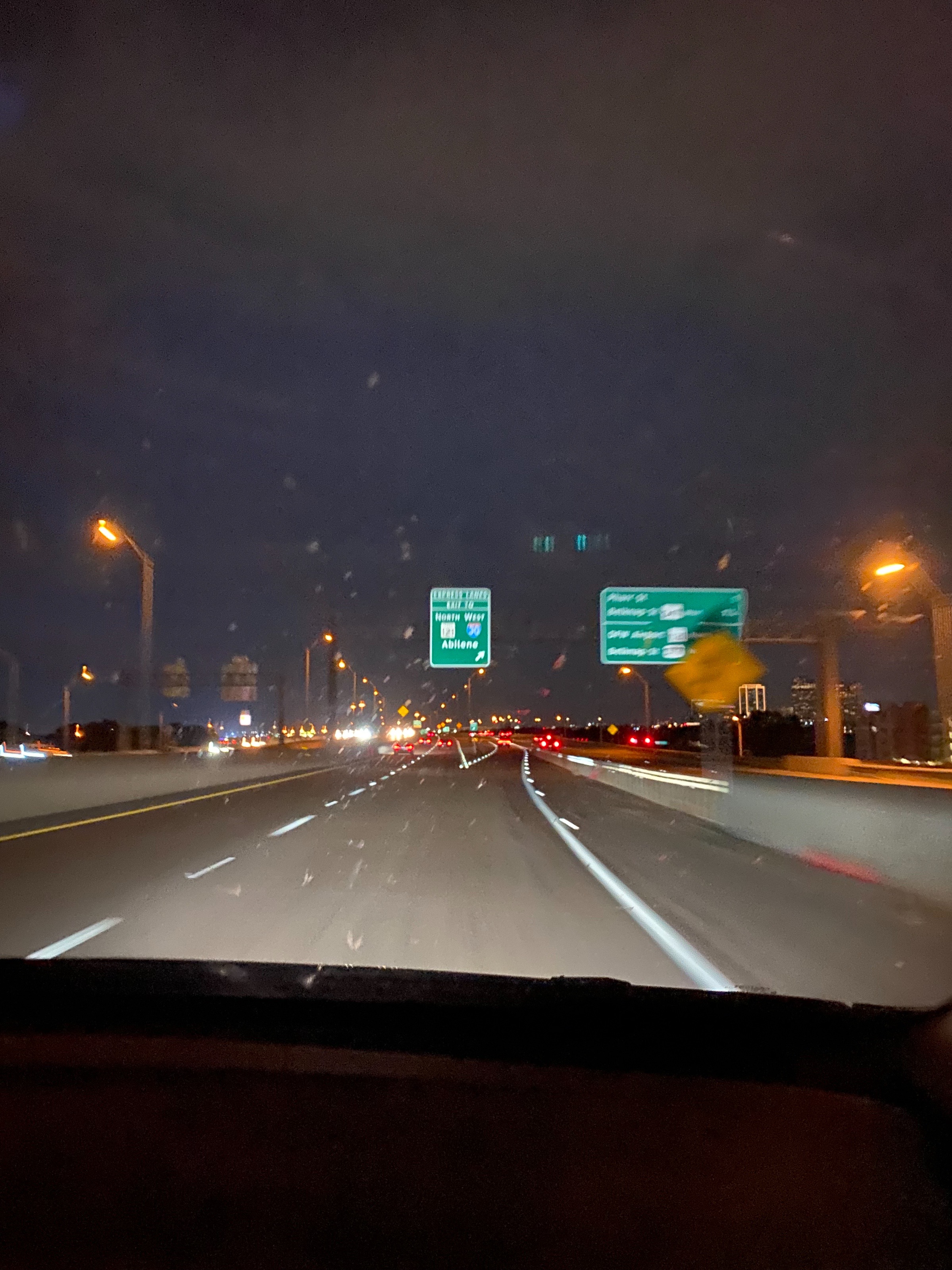 Night view through the windshield of a highway with green overhead signs